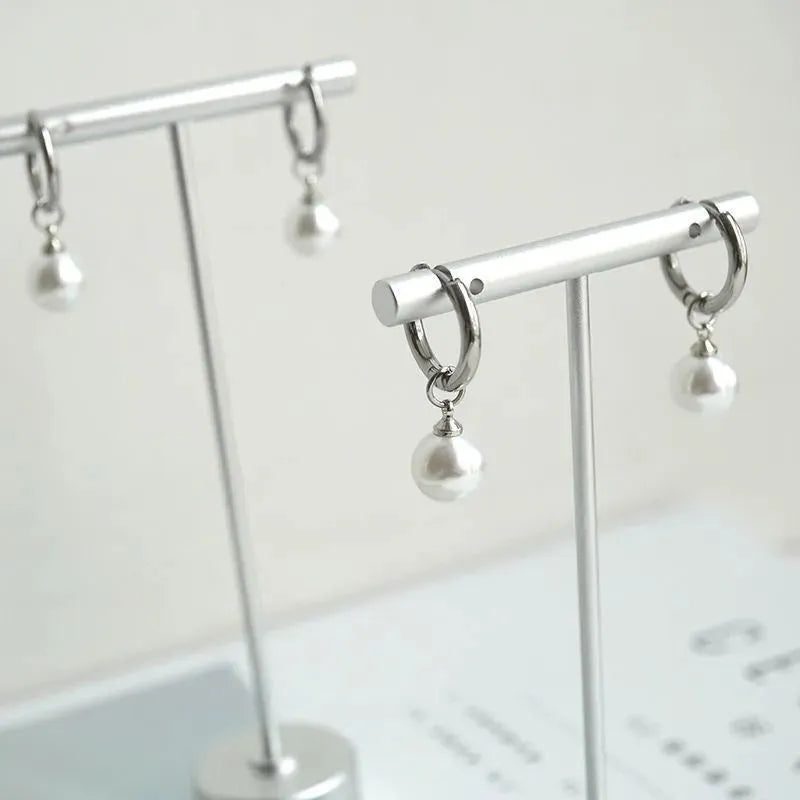 Geometric women's pearl earrings with titanium steel posts on a white background.