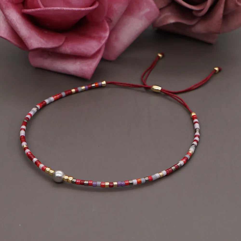 Women's handmade bohemian bracelet with colourful geometric glass and glaze beads on a wrist.