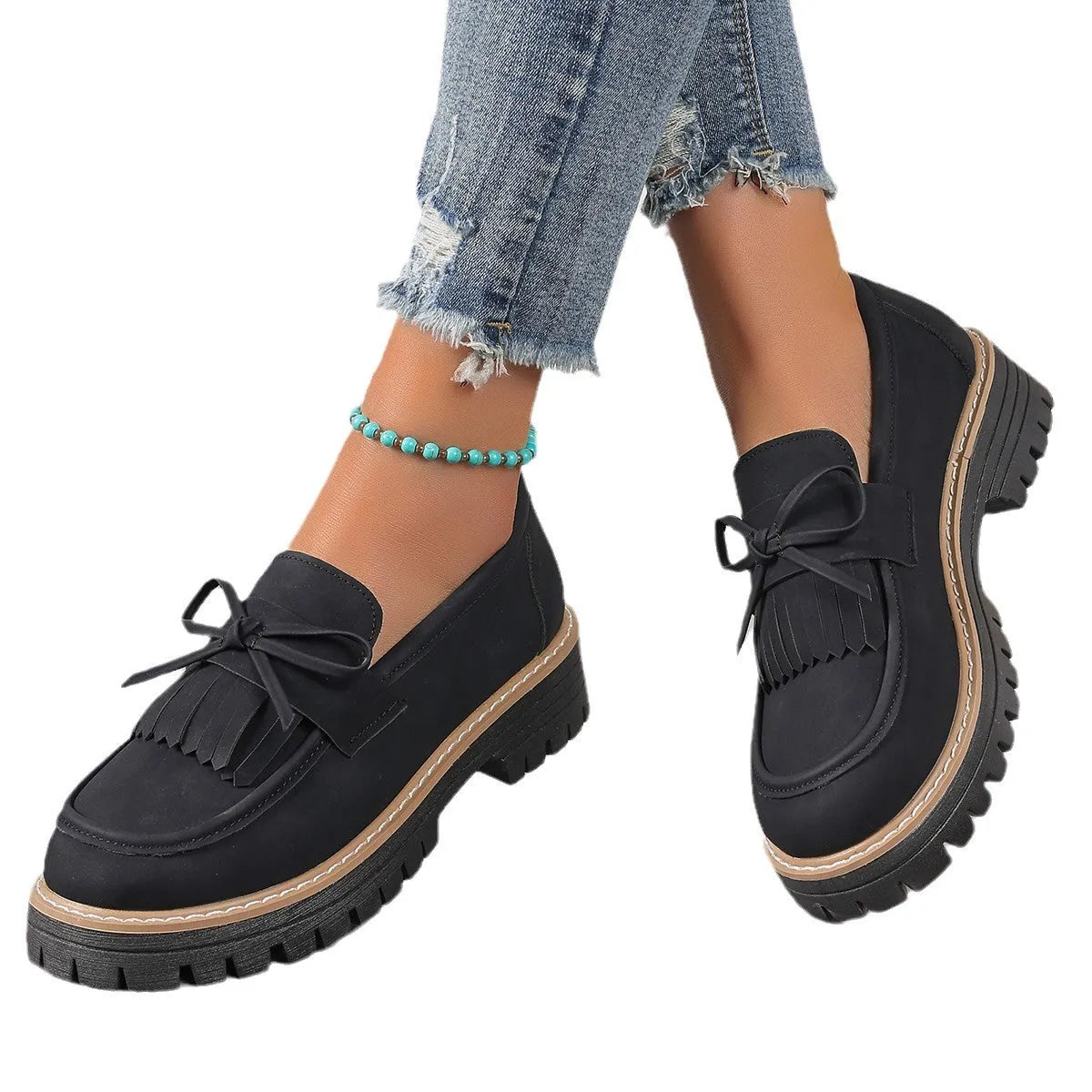 Black and brown women's loafers with tassel and bowknot decoration on a chunky low heel.
