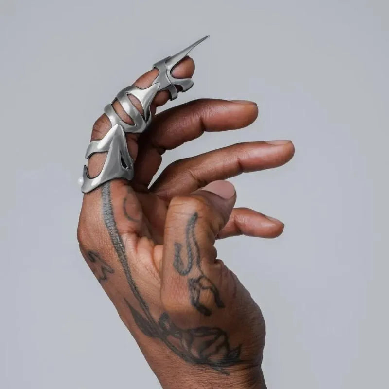 Silver colour alloy metal punk armour finger stall ring on a finger.
