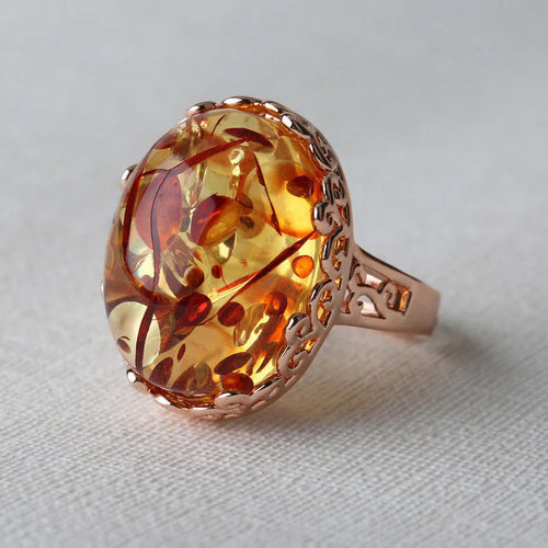 Close-up of a beeswax amber ring with a genuine amber stone on an alloy band, showing retro ethnic style.