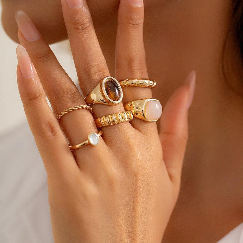 Six geometric alloy rings with light gold electroplated finish arranged irregularly