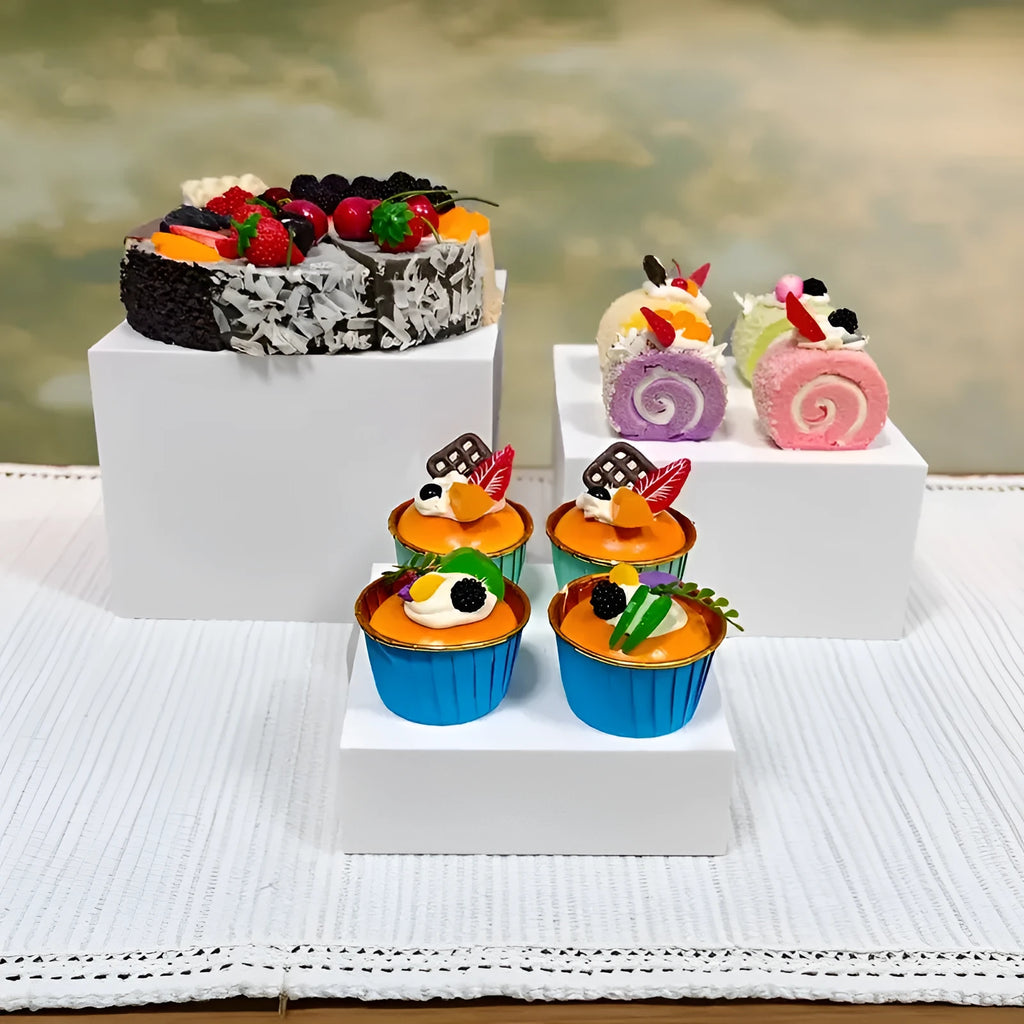 Six white plastic cube dessert display stands in graduated sizes from 3 to 8 centimetres.
