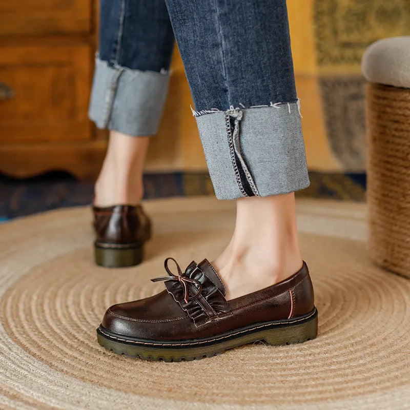 Black and brown women's round toe leather shoes with a chunky flat heel and low upper.