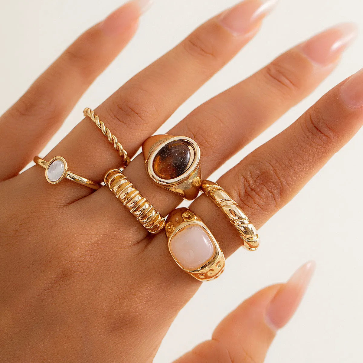 Six geometric alloy rings with light gold electroplated finish arranged irregularly