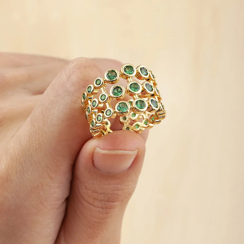 Gold-coloured wide band copper ring with large green zircon stones in a three-layer setting.
