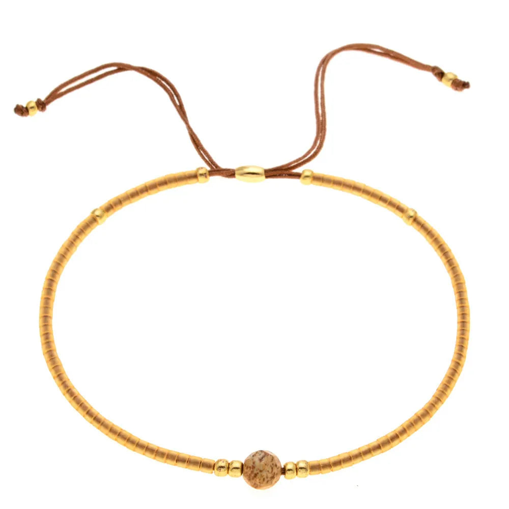 Women's handmade bohemian bracelet with colourful geometric glass and glaze beads on a wrist.
