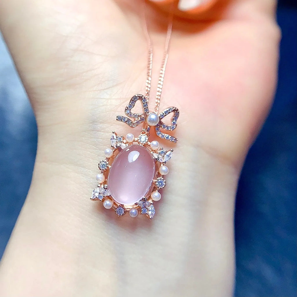 Close-up of a geometric silver pendant with a pink rose quartz stone and rose gold plating on a chain.