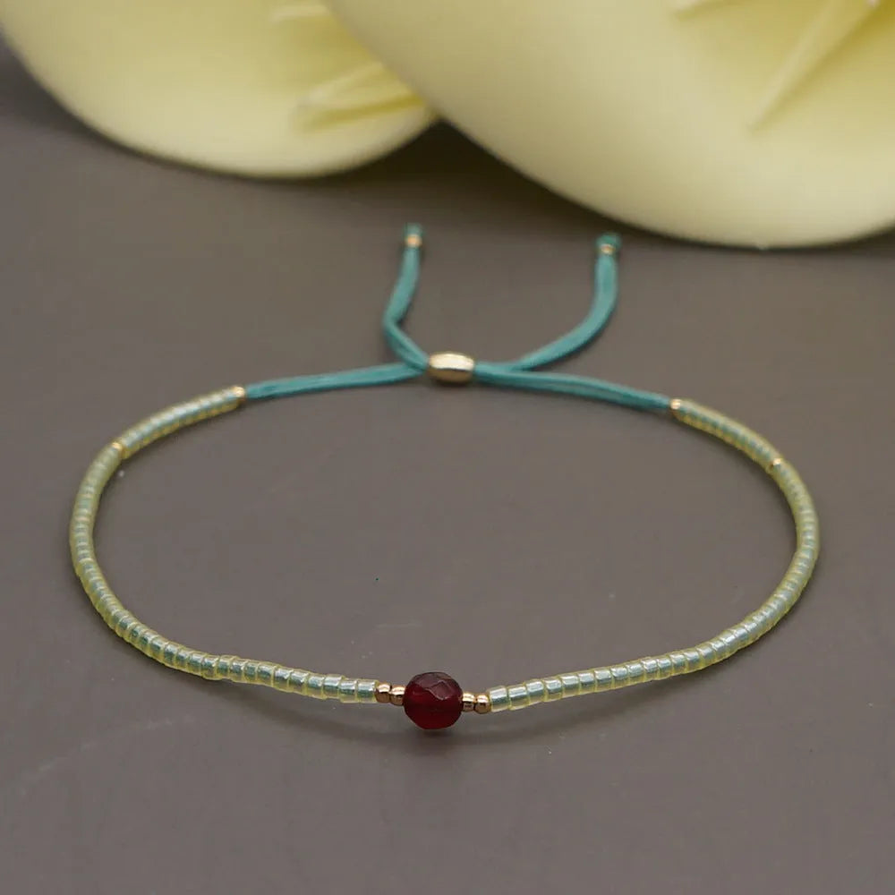 Women's handmade bohemian bracelet with colourful geometric glass and glaze beads on a wrist.