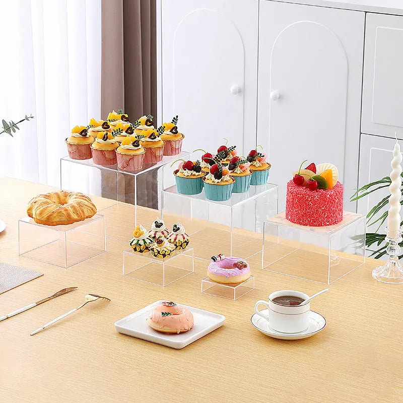 Six white plastic cube dessert display stands in graduated sizes from 3 to 8 centimetres.