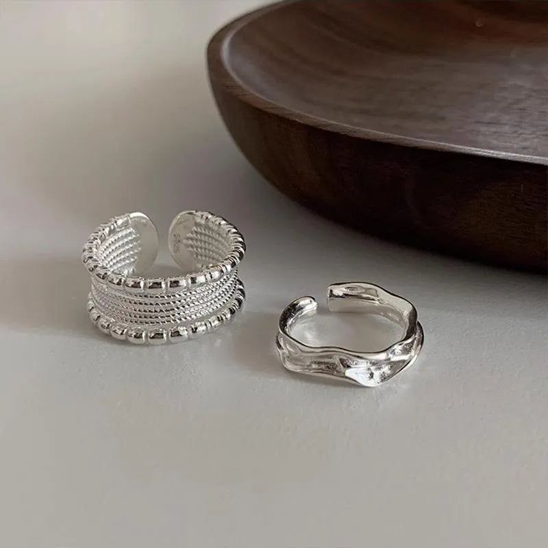 Adjustable geometric copper alloy ring with woven twisted multilayer design on a woman's hand.