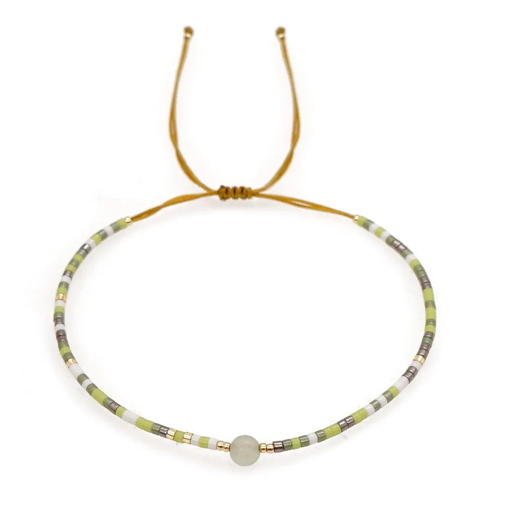 Women's handmade bohemian bracelet with colourful geometric glass and glaze beads on a wrist.