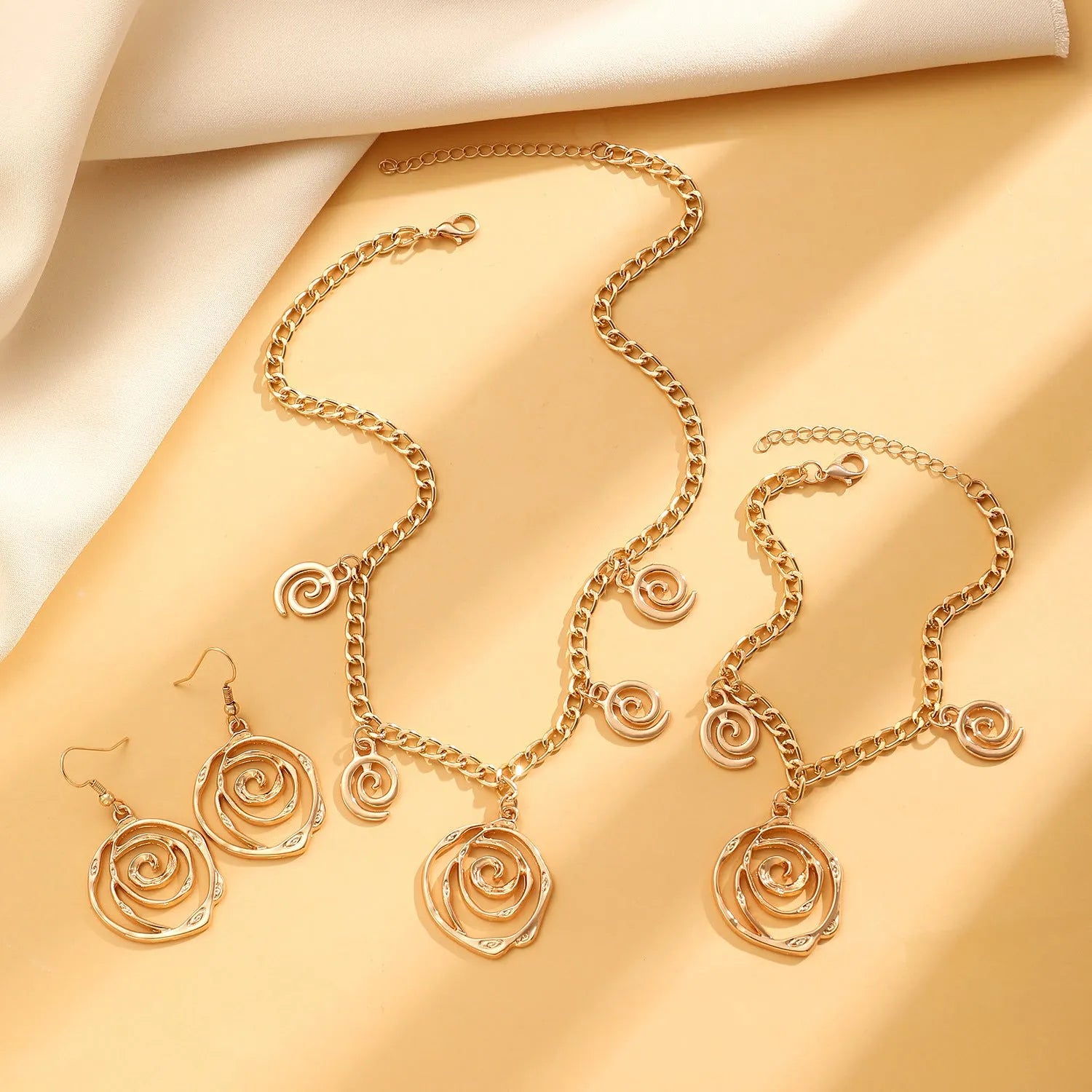 Women's spiral donut jewellery set showing bracelet, earrings, and adjustable necklace in gold tone