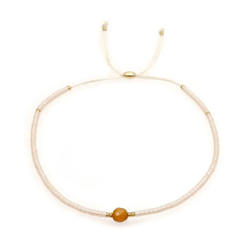 Women's handmade bohemian bracelet with colourful geometric glass and glaze beads on a wrist.