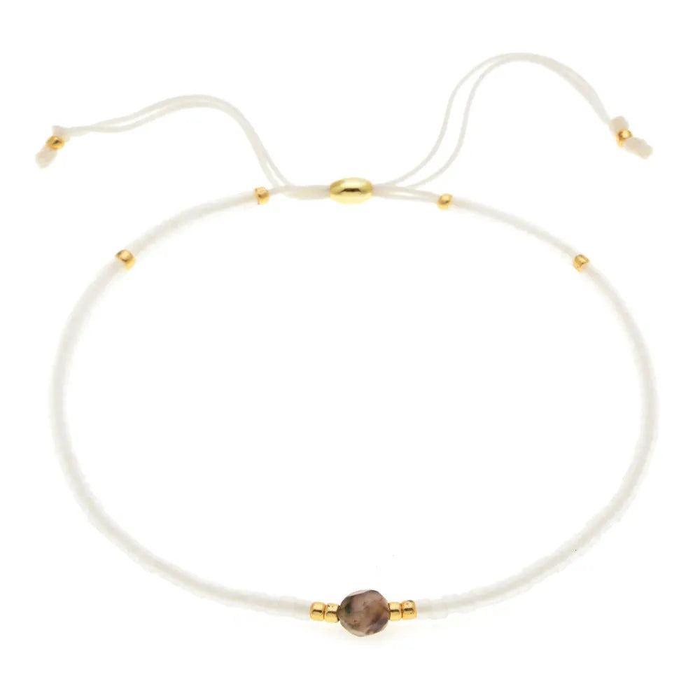 Women's handmade bohemian bracelet with colourful geometric glass and glaze beads on a wrist.