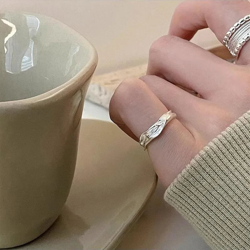 Adjustable geometric copper alloy ring with woven twisted multilayer design on a woman's hand.