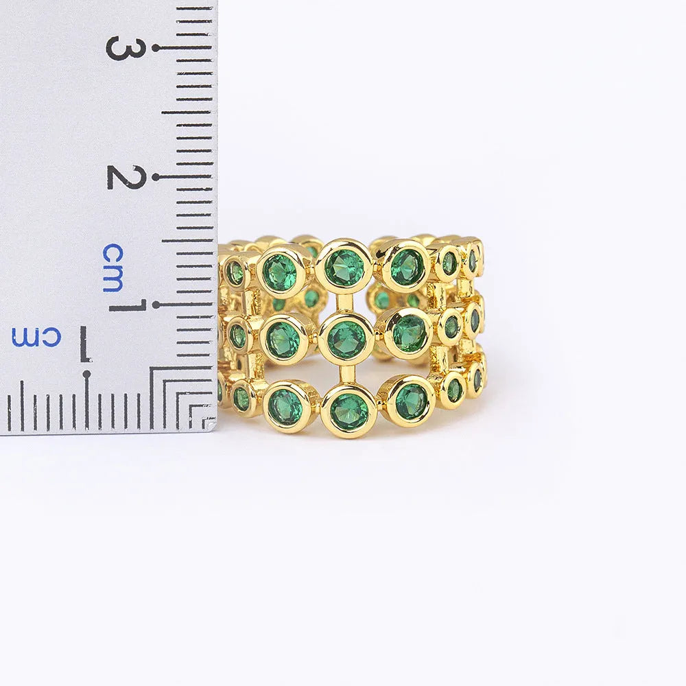 Gold-coloured wide band copper ring with large green zircon stones in a three-layer setting.