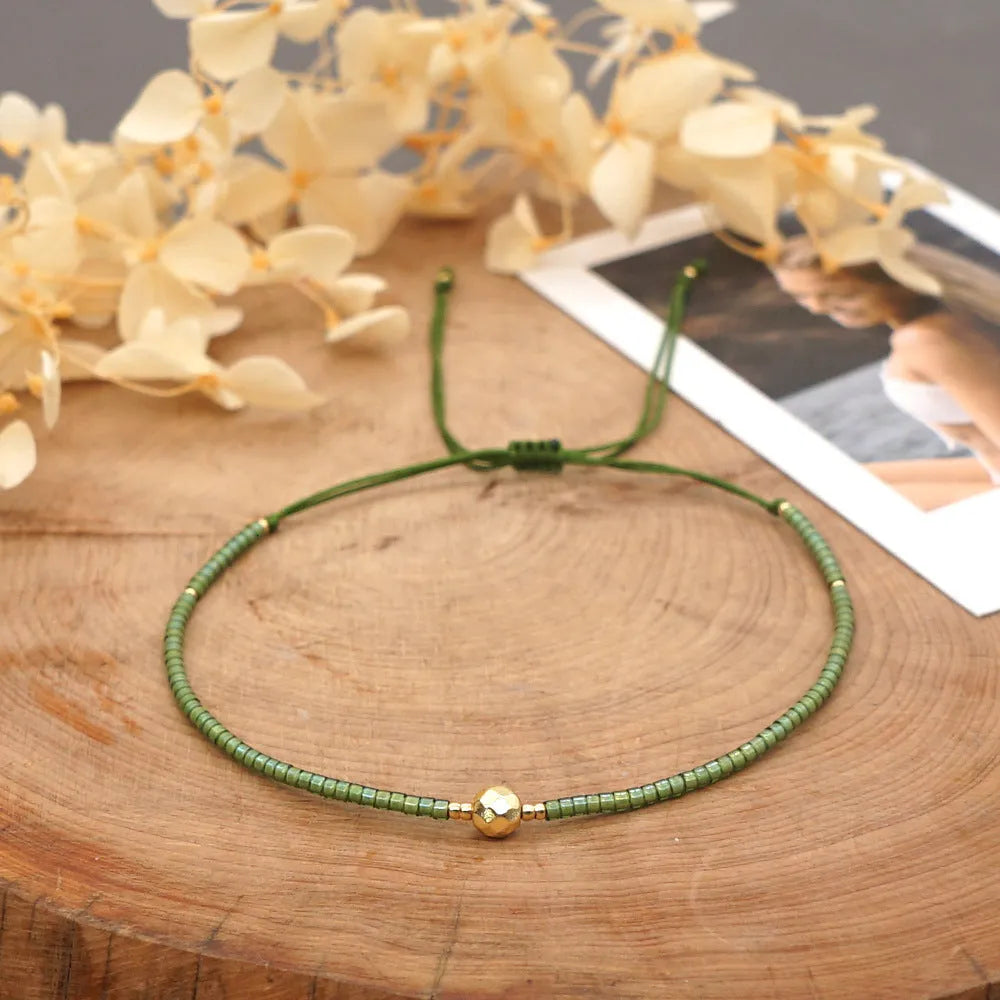 Women's handmade bohemian bracelet with colourful geometric glass and glaze beads on a wrist.