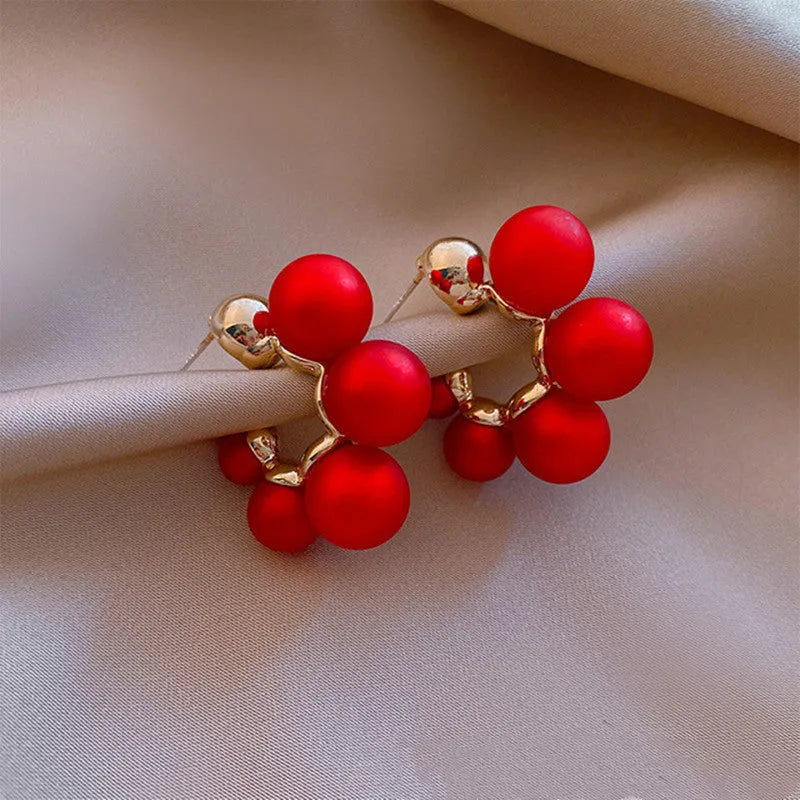 A pair of red alloy drop earrings featuring a small bell charm on a stud fitting.