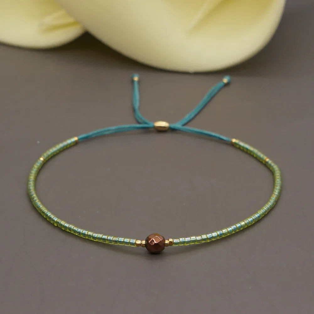 Women's handmade bohemian bracelet with colourful geometric glass and glaze beads on a wrist.