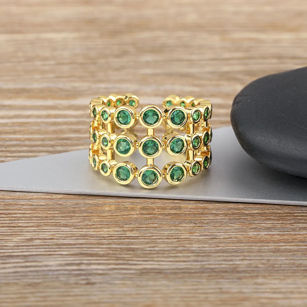 Gold-coloured wide band copper ring with large green zircon stones in a three-layer setting.