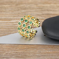 Gold-coloured wide band copper ring with large green zircon stones in a three-layer setting.