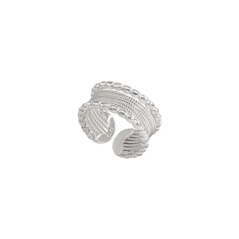 Adjustable geometric copper alloy ring with woven twisted multilayer design on a woman's hand.
