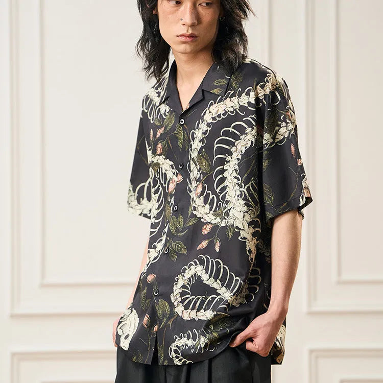 Man wearing a loose fit short sleeve Cuban collar shirt with a snake bone and floral pattern print.