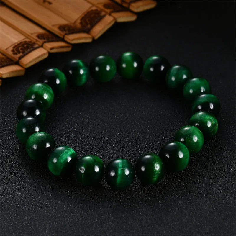 Green tiger eye stone bracelet with geometric beads on a wrist.