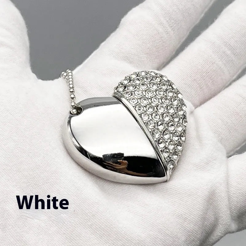 A heart-shaped silver USB flash drive with a brick pattern, shown next to a laptop.