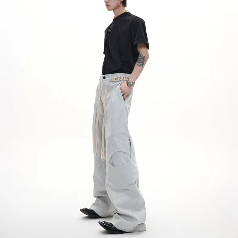 Men's dark blue straight-leg jeans with heavy 3D cutting, showing zipper decoration and tassel detail on a loose fit.