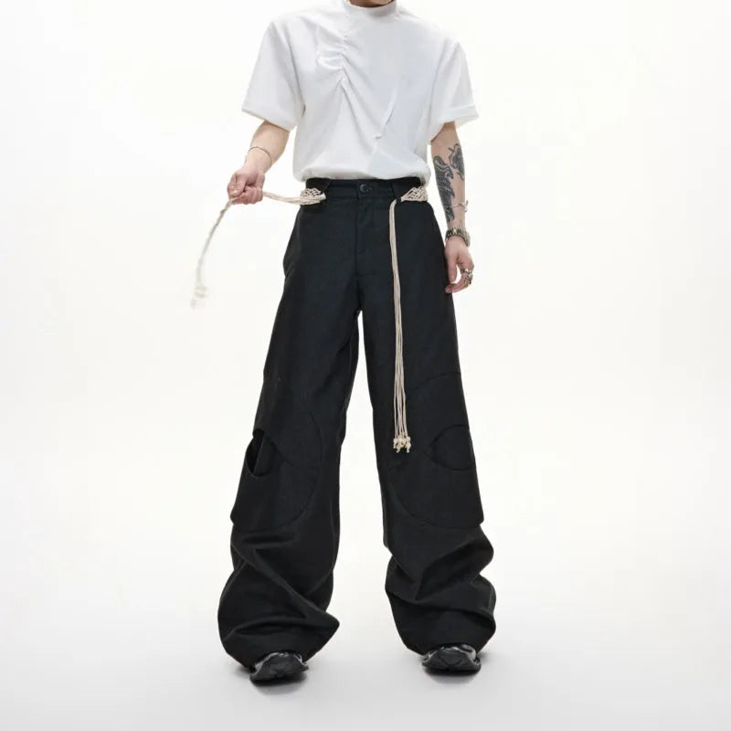 Men's dark blue straight-leg jeans with heavy 3D cutting, showing zipper decoration and tassel detail on a loose fit.