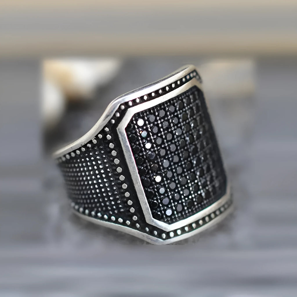Black alloy ring with copper inlay and a central zircon stone, shown in size 10.