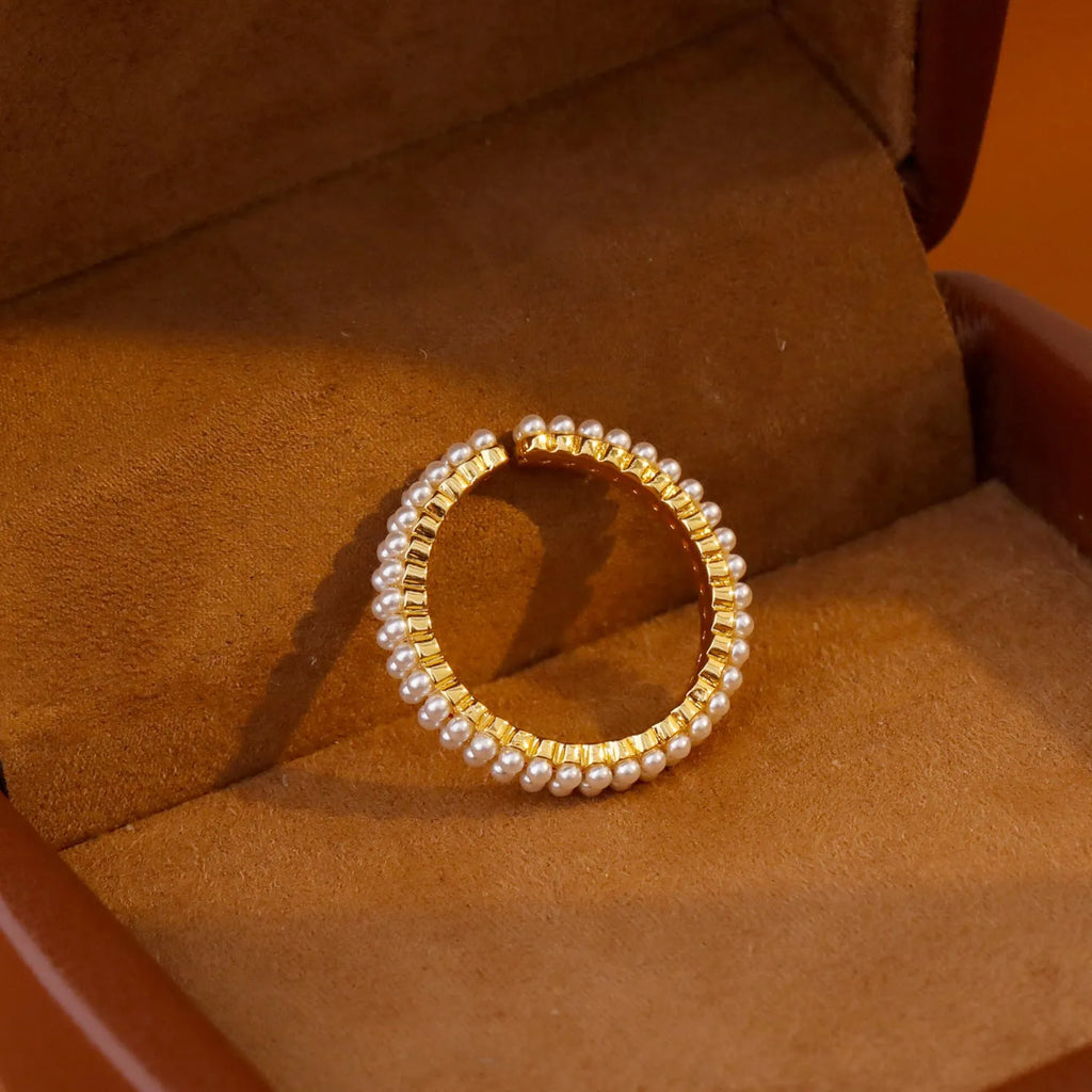 Gold-coloured women's open ring with geometric design and a round pearl-like bead.