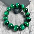 Green tiger eye stone bracelet with geometric beads on a wrist.