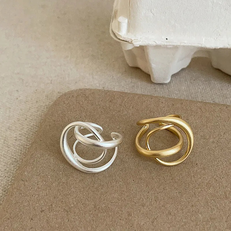 Geometric open ring for women with 3D interlaced matte metal design in gold or silver.