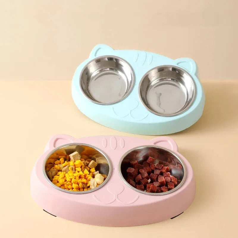 Blue plastic double bowl pet feeding tray for cats and dogs with non-slip rubber feet on a floor.