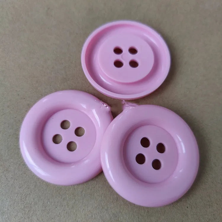 Oversized round plastic button with four holes in various colours and sizes from 38mm to 70mm.
