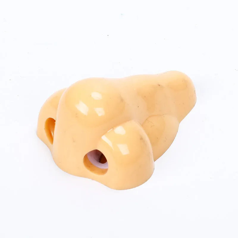 Flesh coloured plastic pencil sharpener with big nostril hole showing compact geometry shape
