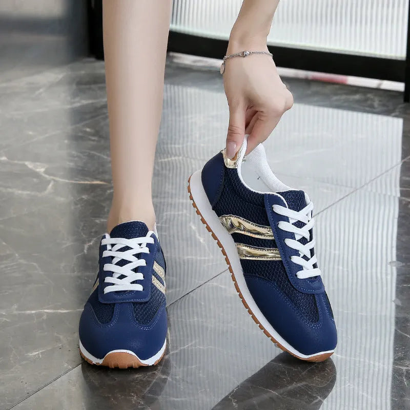 Blue women's lace-up tennis shoes with cross shoulder straps and a flat rubber sole.