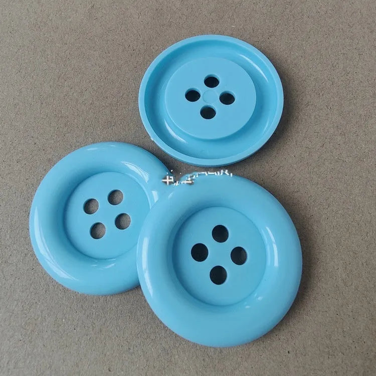 Oversized round plastic button with four holes in various colours and sizes from 38mm to 70mm.