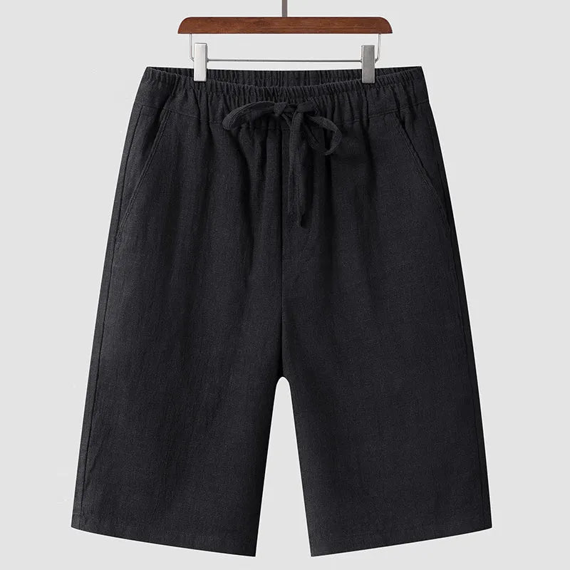 Men's beige linen casual shorts with loose cropped fit and elastic waistband laid flat