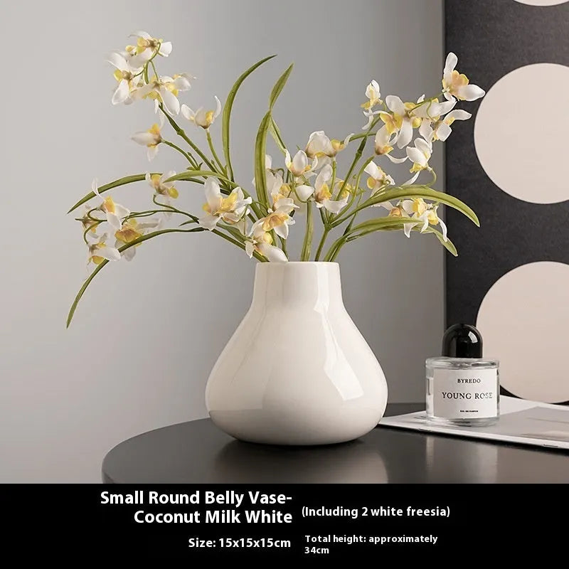 Ceramic round belly vase in black or white with artificial orchid stems on wooden surface