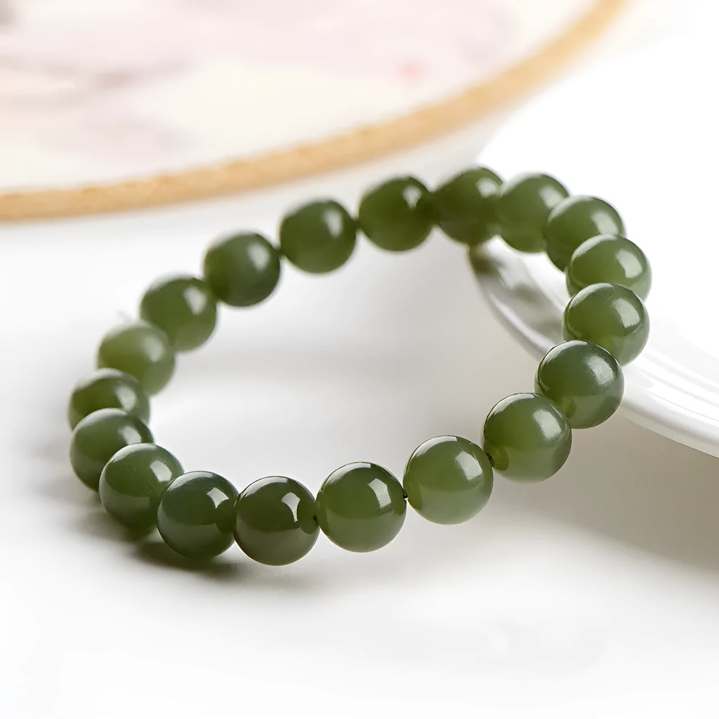 Polished Hetian jade ball bead bracelet in light and deep clear water colours on a wrist.