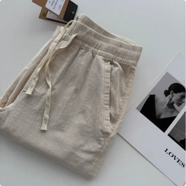 Men's beige loose-fit straight-leg casual pants with a drawstring waistband on a hanger.