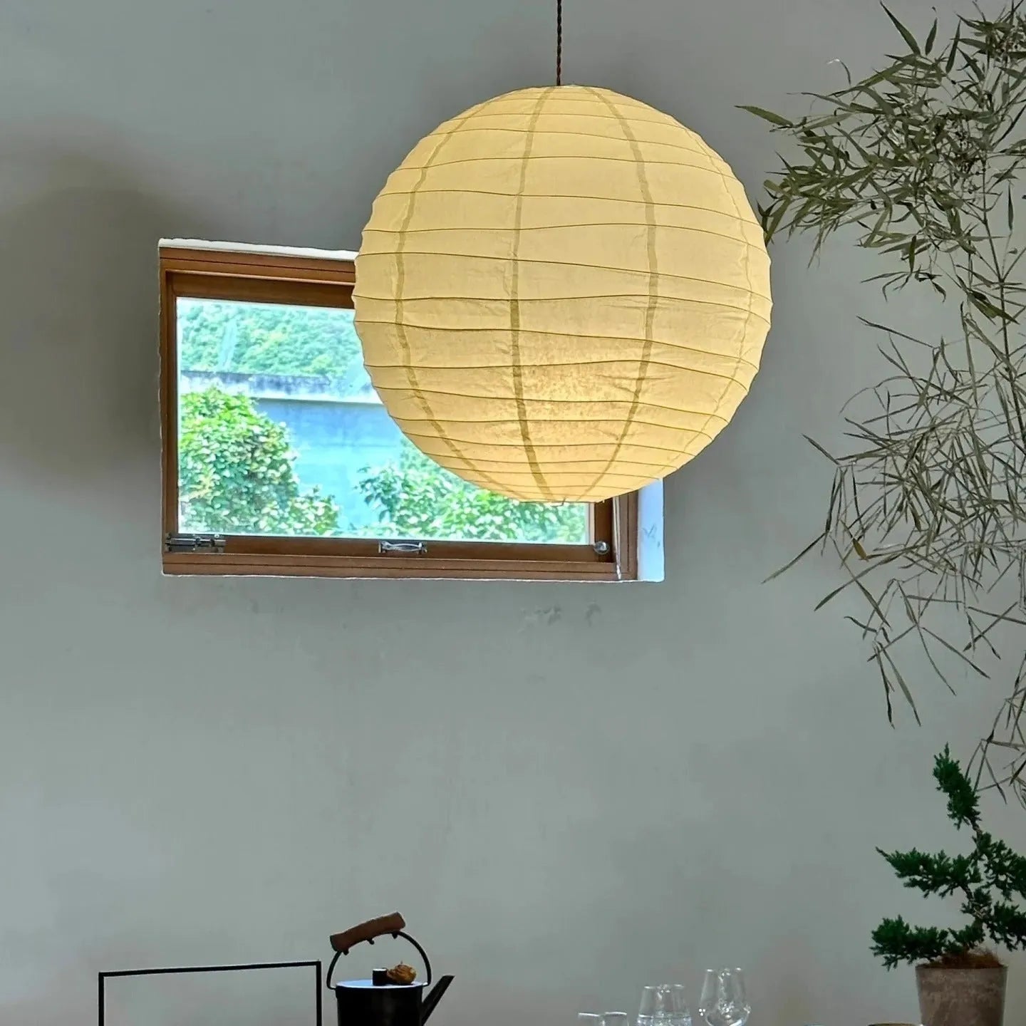 Japanese style white rice paper pendant chandelier with a woven frame, shown in a room setting.