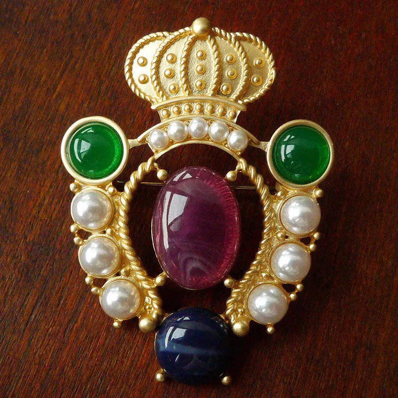 A vintage-style baroque brooch made of zinc alloy in a diamond shape on a fabric background.