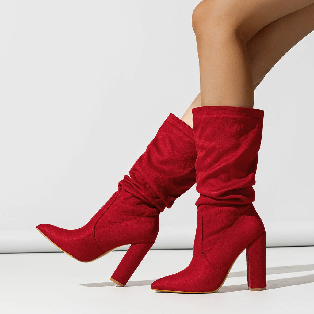 Women's black suede knee-high boots with a chunky high heel and pointed toe on a plain background.