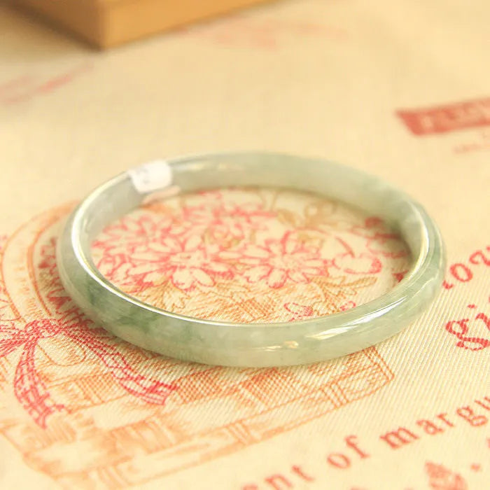 Green jade waxy geometric bead bracelet with adjustable cord on a plain background.