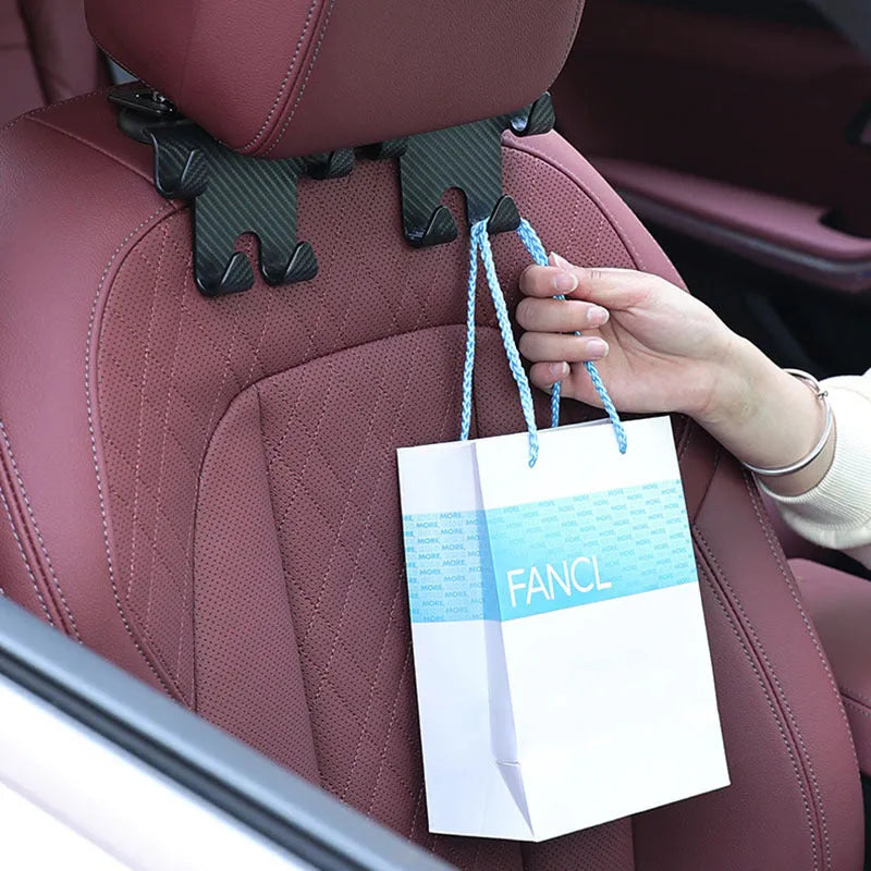 Black ABS plastic car hook and phone holder bracket mounted behind a car seat headrest.